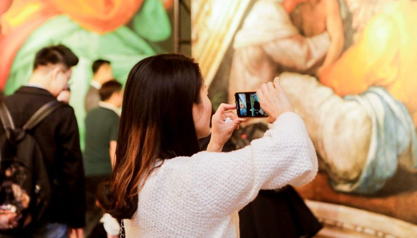 Woman using smartphone to take a photo in an art exhibit