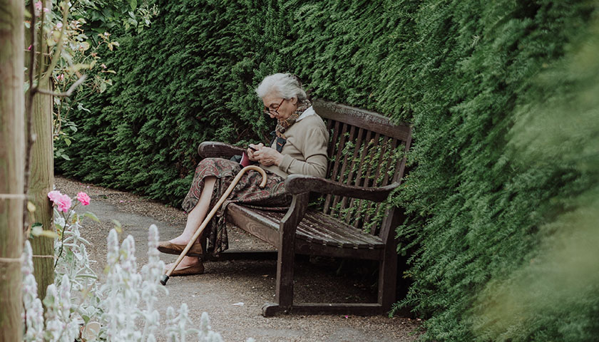 Old woman sitting on brown bench