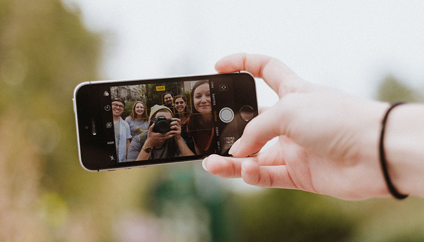 Person holding a phone, group of people taking a photo together