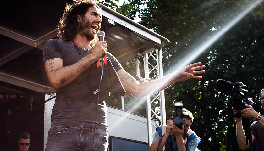 Russell Brand Tells His Growing Audience to Question What They’re Told